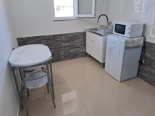 a kitchen with a counter and a stool and a microwave at Il Quadrifoglio House Airport in CTA