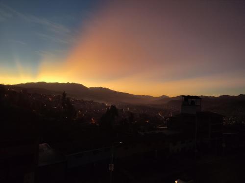 a sunset over a city with mountains in the background at linda house cusco in Cusco