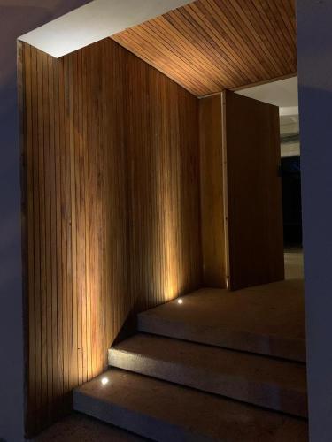 a room with a wooden wall and stairs with lights at Estúdio ao lado da Praia - Rifaina in Rifaina