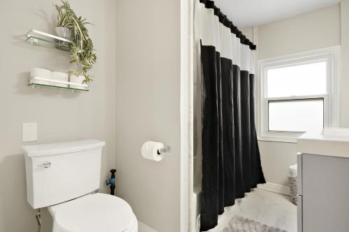 a bathroom with a toilet and a black shower curtain at Separate 3BR Family Friendly Apartments, Separate Floors, 5 Minutes Walk to The Fallsview with Free Parking & Wine in Niagara Falls