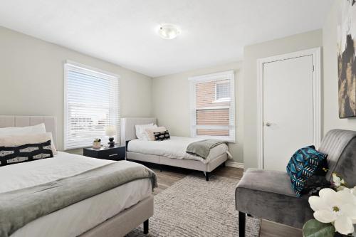 a bedroom with two beds and a chair at Separate 3BR Family Friendly Apartments, Separate Floors, 5 Minutes Walk to The Fallsview with Free Parking & Wine in Niagara Falls