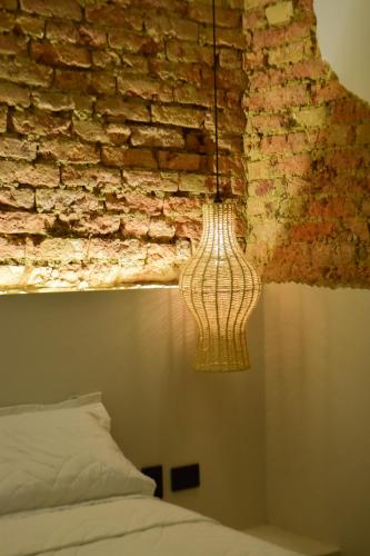 a lamp hanging from a brick wall next to a bed at Casa Zoé Hotel Boutique in Villeta