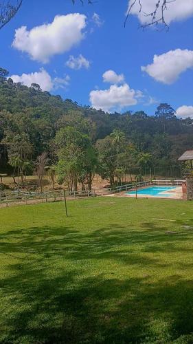 a grassy field with a swimming pool and trees at Suite 5 in Nova Friburgo