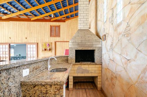 eine Küche mit einer Spüle und einem Kamin in der Unterkunft Piscina e mar em único lugar in Penha