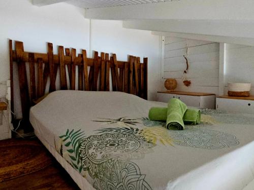a bedroom with a bed with a green pillow on it at Kaza Lenah villa 2 chambres dont une en mezzanine, piscine et cuve tampon, Saint-François in Saint-François