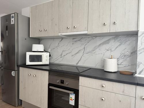 a kitchen with a microwave and a refrigerator at El Puertito Beach Retreat in Agaete