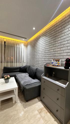 a living room with a couch and a brick wall at Racine Studio bd Anfa in Casablanca