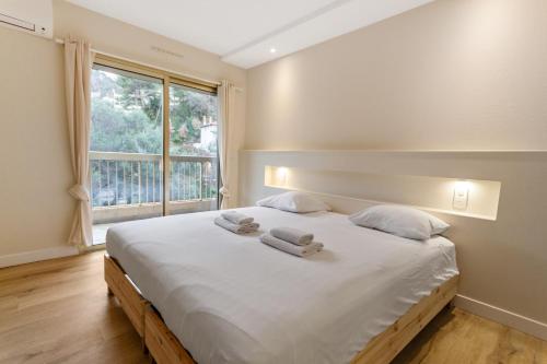 une chambre avec un grand lit blanc avec des serviettes dessus dans l'établissement Le Magali - Hypercentre - Parking - Spacious - AC, au Cannet