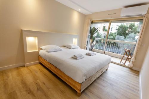 une chambre avec un grand lit et une grande fenêtre dans l'établissement Le Magali - Hypercentre - Parking - Spacious - AC, au Cannet