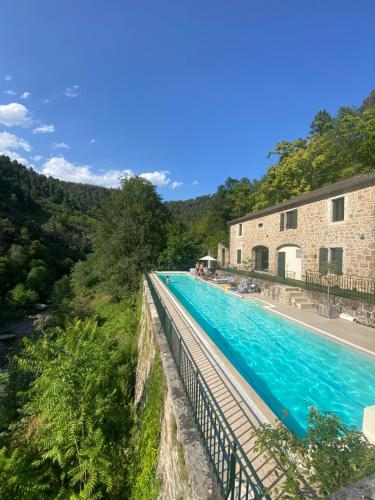 - une piscine à côté d'un bâtiment et d'une rivière dans l'établissement Le Buis Domaine, à Saint-Sauveur-de-Montagut