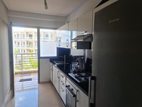 a kitchen with white cabinets and a black counter top at superbe appartement vue piscine in Bouznika