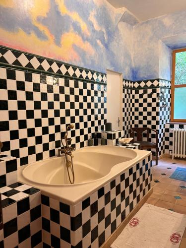 La salle de bains est pourvue d'une grande baignoire et de murs en damier. dans l'établissement Le Buis Domaine, à Saint-Sauveur-de-Montagut