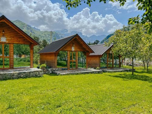 a row of log cabins with mountains in the background at Logu i Harushave in Theth