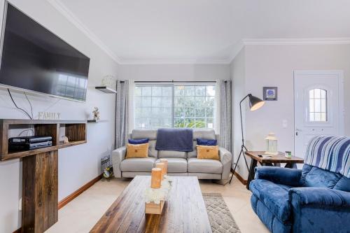 a living room with a blue couch and a tv at La Casita Felizola- Charming Coastal Escape in São Pedro