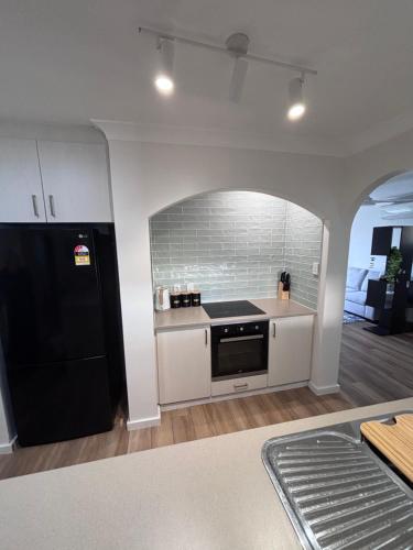 a kitchen with a black refrigerator and a stove at Cozy 3-Bed House in Halls Head in Mandurah