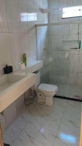 a white bathroom with a toilet and a sink at Casa da Marília in Porto Seguro