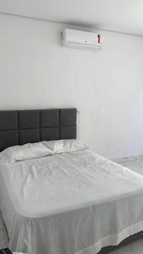 a white bed with a black headboard in a bedroom at Casa da Marília in Porto Seguro