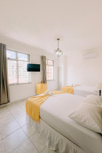 a white bedroom with a large bed with yellow sheets at Apto Amplo e confortável no centro de Salvador in Salvador