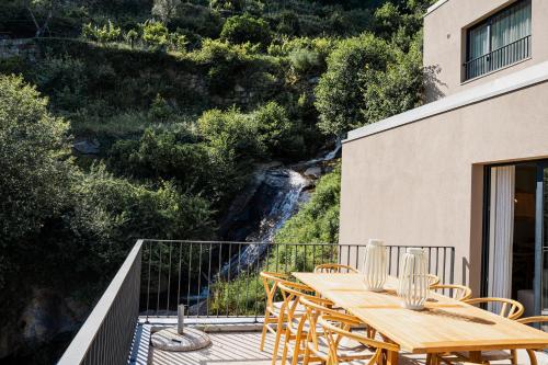 a wooden table and chairs on a balcony with a waterfall at Quinta da Ribeirinha - Douro River in Paços de Gaiolo
