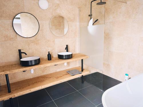 deux lavabos dans une salle de bain avec deux miroirs dans l'établissement La maison du Canal- 9 pers- Capestang, à Capestang