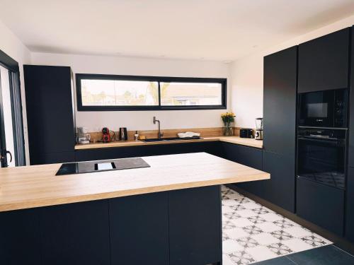 une cuisine avec des armoires noires et un comptoir en bois dans l'établissement La maison du Canal- 9 pers- Capestang, à Capestang
