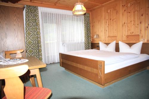 ein Schlafzimmer mit einem großen Bett und einem Tisch in der Unterkunft Berghaus Maria in Pettneu am Arlberg