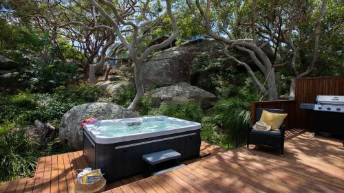 a hot tub sitting on a deck next to a garden at Amazing Views, Stunning Beaches and Beautiful Bushwalks in Hardys Bay