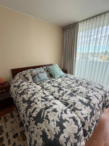 a bedroom with a bed with a black and white blanket at departamento en osorno in Osorno