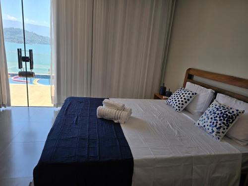 ein Schlafzimmer mit einem Bett und Meerblick in der Unterkunft Maravilhosa casa linear 5 suítes em Angra in Angra dos Reis