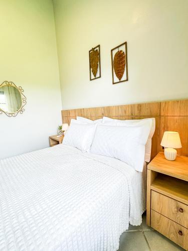 a bedroom with a bed with white sheets and a mirror at RJ Sitio Refugio da Serra fazendinha in Rancho Queimado