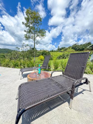 two wicker chairs and a table with a drink on it at RJ Sitio Refugio da Serra fazendinha in Rancho Queimado