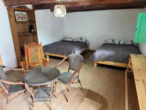 a room with two beds and a table and chairs at Cabañas Rincón Metztitlán in Azolzintla