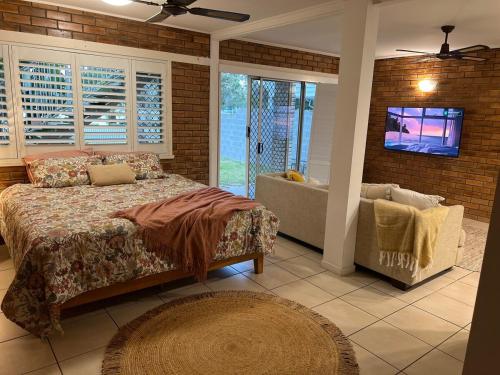 a bedroom with a bed and a tv and a couch at Tallebudgera Creek Escape in Gold Coast