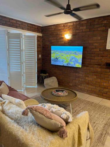a living room with a couch and a flat screen tv at Tallebudgera Creek Escape in Gold Coast