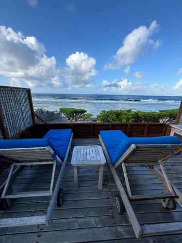 two chairs and a table on a deck with the ocean at Vahaui Paradis in Avatoru