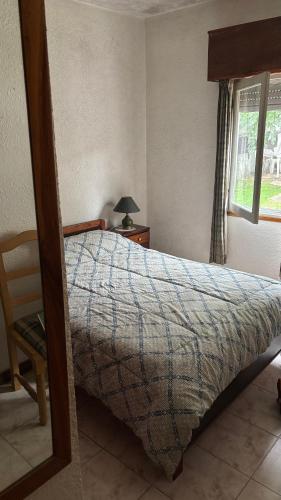 a bedroom with a bed and a chair and a window at Casa en Piriápolis in Piriápolis