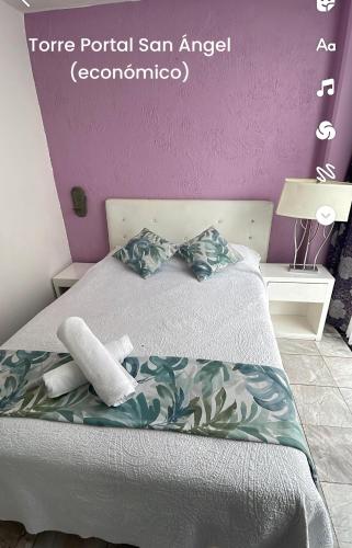 a bedroom with a bed with a purple wall at Satya Suites & Portal San Angel Flats in Mexico City