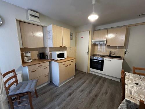- une petite cuisine avec des appareils blancs et des armoires en bois dans l'établissement Charmant T2 avec WIFI et parking au centre de La Roche-Posay - FR-1-541-159, à La Roche-Posay