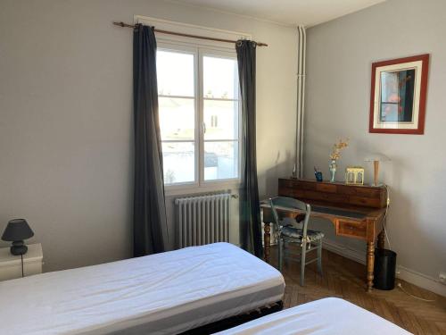 Charmant appartement lumineux et spacieux au centre de Royan - FR-1-738-44 في رويان: غرفة نوم بها سرير ومكتب ونافذة