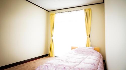 a bedroom with a bed and a large window at 新居浜旧街道コミュニティハウス大倉屋 in Niihama