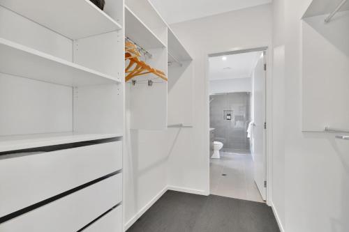 a white bathroom with white cabinets and a toilet at Chic Family Friendly 4BR Retreat Near Redcliffe in Scarborough