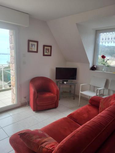 a living room with a red couch and a television at Les Balcons de la Mer in Erquy