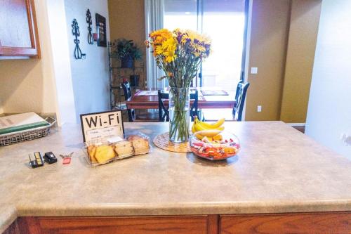 a counter with a vase of flowers and a bowl of fruit at Quiet Gated Community Minutes from Falcon Fld in Mesa