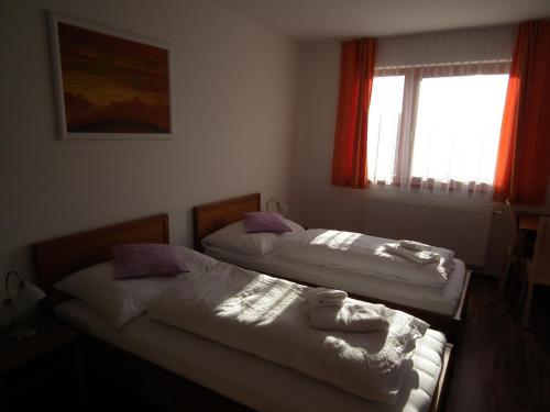 two beds in a room with a window at Baláca Panzió in Veszprém