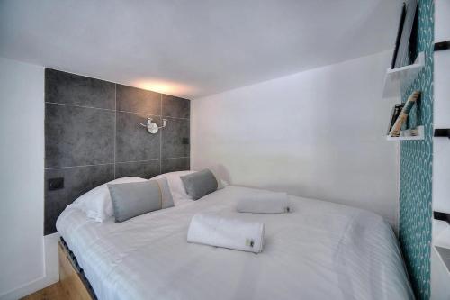 une chambre avec un lit blanc avec deux oreillers dessus dans l'établissement Studio Colette mezzanine - 500m FROM THE BEACH, à Cannes