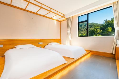 due letti in una stanza con finestra di Shenzhen Yusu Linting Seaview Inn Judiaosha Branch a Shenzhen