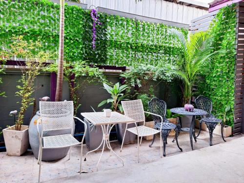 a patio with tables and chairs and a green wall at Lilac Relax-Residence in Lat Krabang