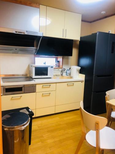 a kitchen with white cabinets and a black refrigerator at Nara House R2 in Kawagoe