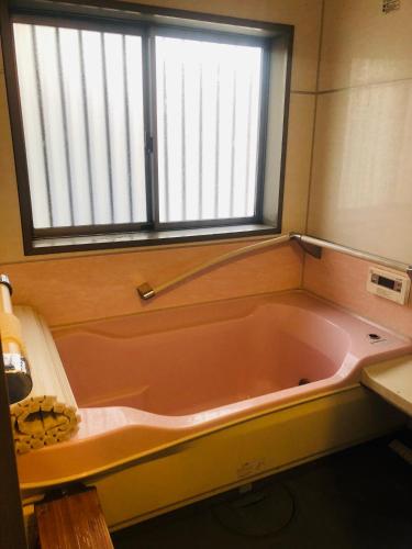 a large pink tub in a bathroom with a window at Nara House R2 in Kawagoe