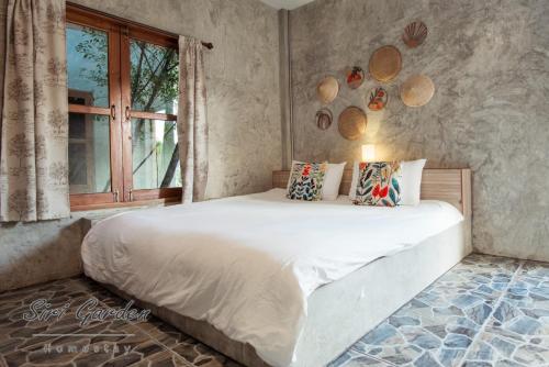 a bedroom with a large bed and a window at บ้านสวนศิริ Siri Garden in Ban Mang